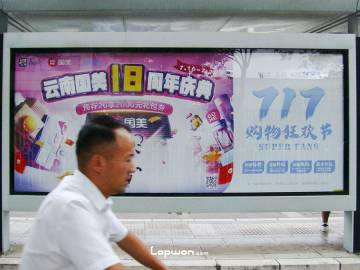 2021年07月08日，云南省昆明市，骑行路过国美广告牌前的人。by Lopwon